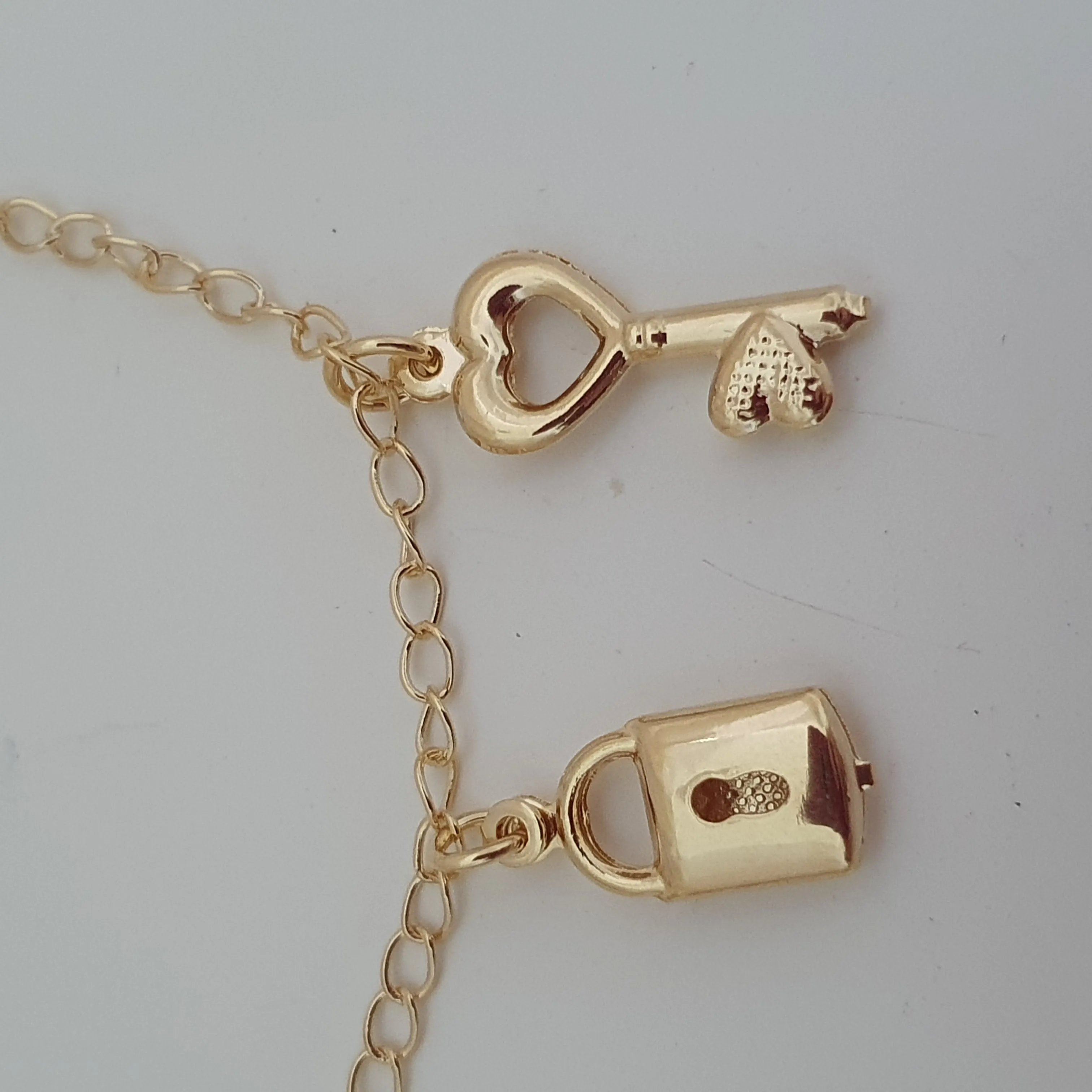 Pulseira com pingente de chave e cadeado com detalhe de coração