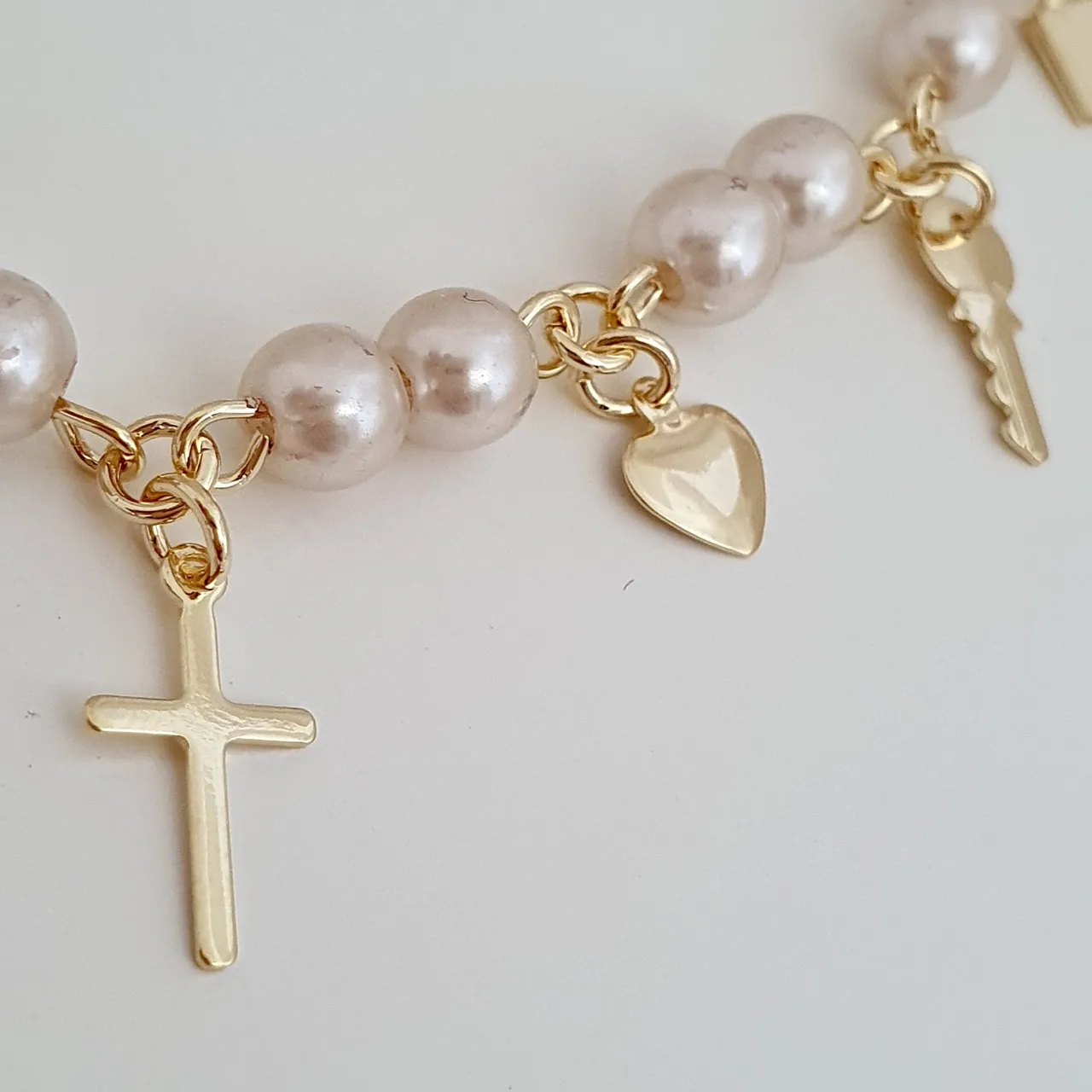 Pulseira pérolas e pingentes cruz, chave, cadeado, coração