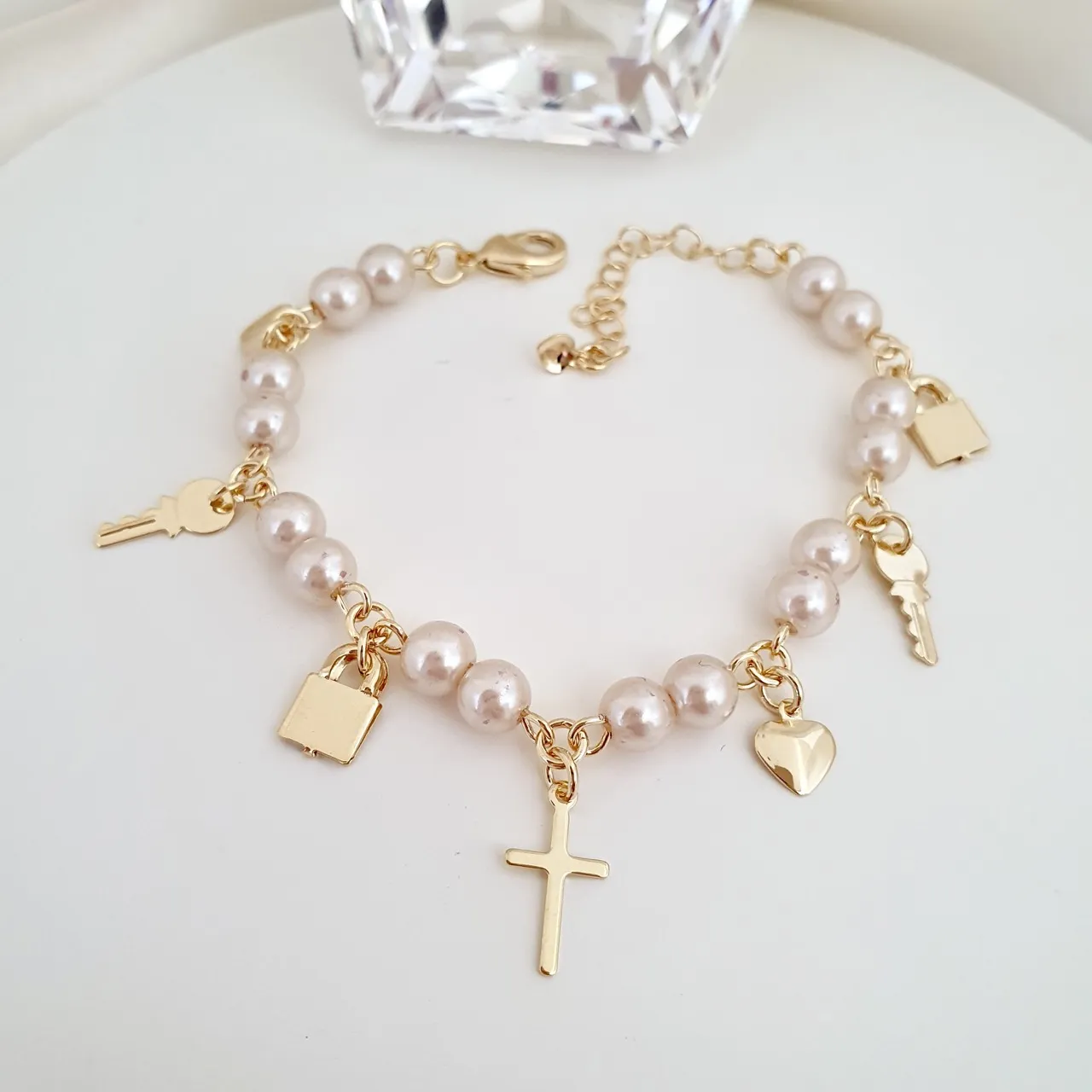 Pulseira pérolas e pingentes cruz, chave, cadeado, coração